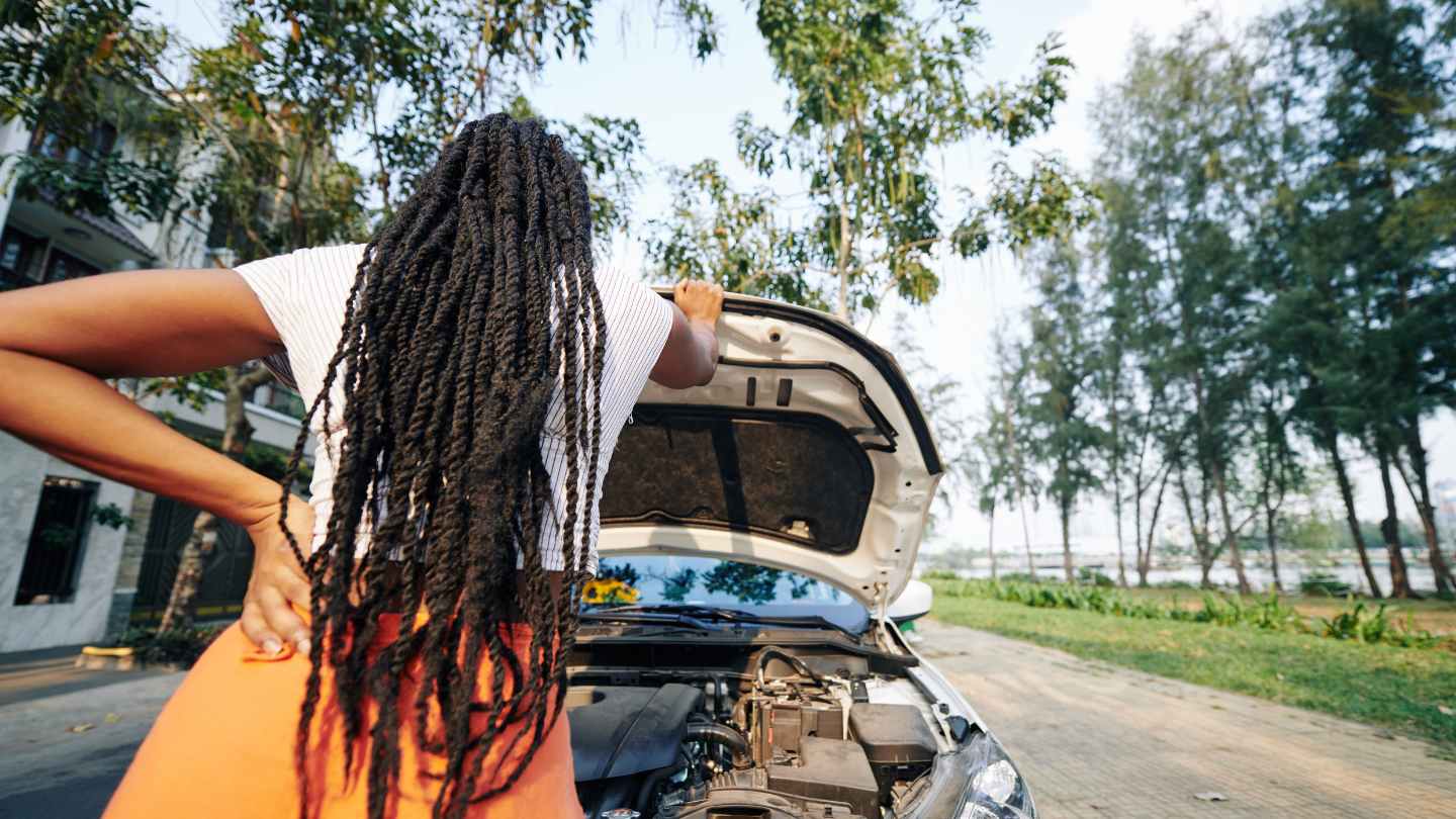 Driver standing beside an open hood after a vehicle breakdown