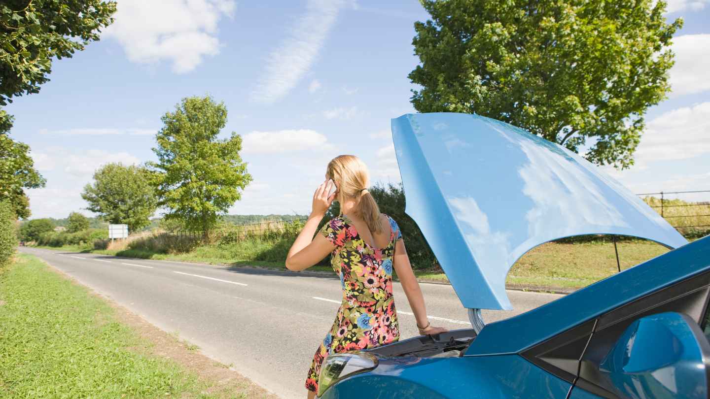 Driver sitting on a car hood while calling for help