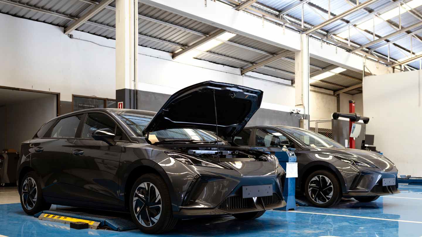 Vehicles in a repair shop with a hood open for inspection