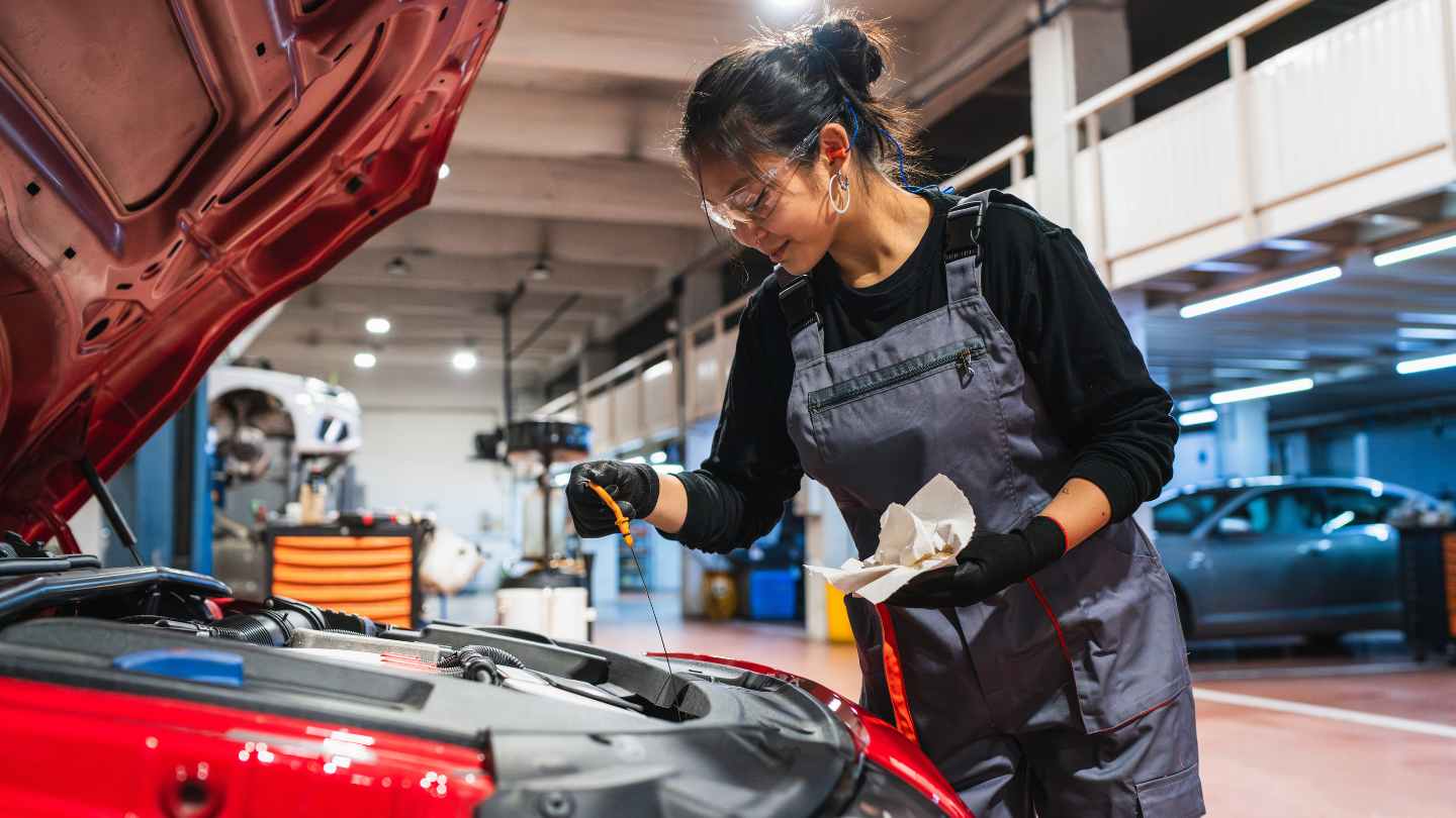 Technician checking vehicle fluids in a service bay