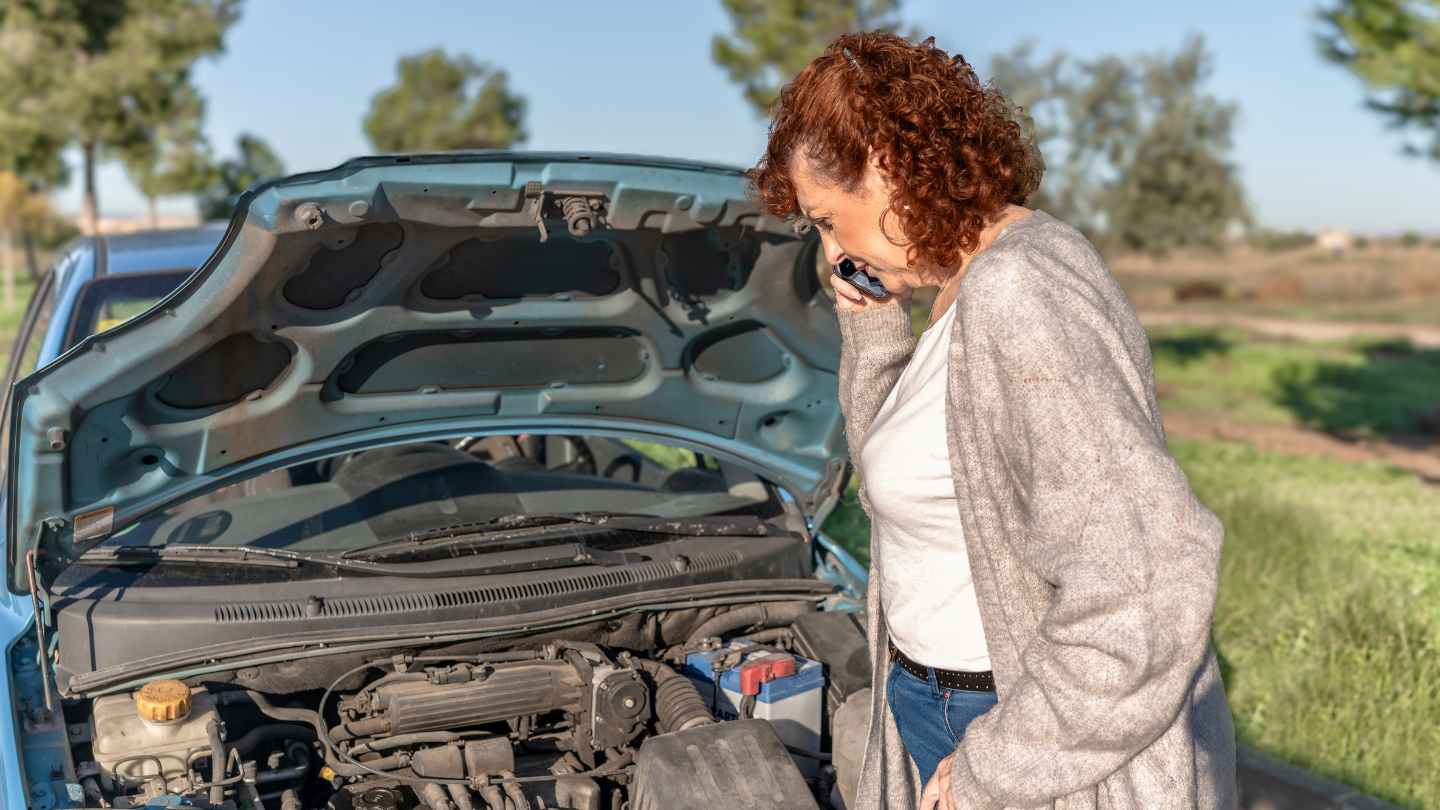 Driver calling for help beside an open hood