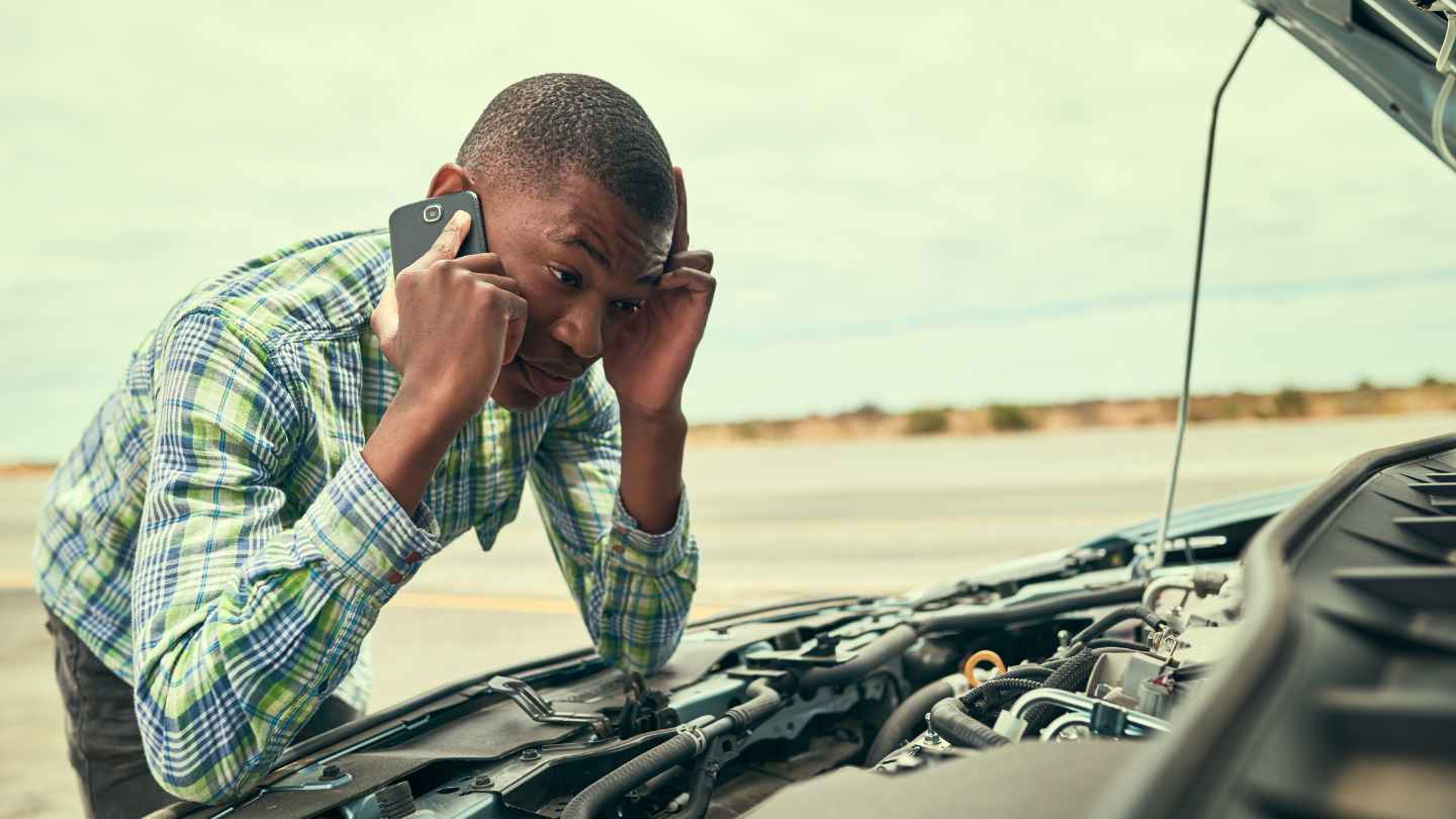 Driver leaning over an open engine while talking on the phone